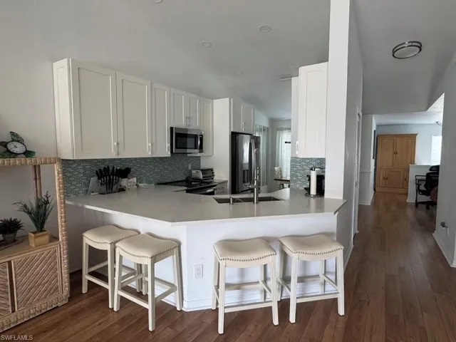 Kitchen featuring a kitchen bar, dark wood finished floors, white cabinetry, and a peninsula