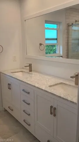Full bathroom featuring double vanity, a shower stall, and light tile patterned floors