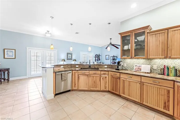 Kitchen with light tile patterned flooring, backsplash, sink, stainless steel dishwasher, and ceiling fan