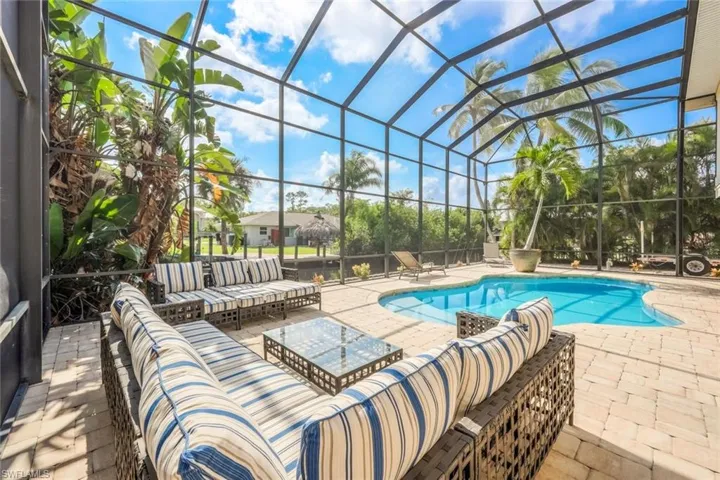 View of pool featuring a patio, glass enclosure, and an outdoor living space