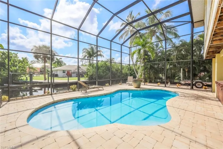 View of pool with glass enclosure and a patio