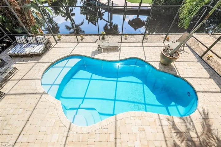 View of swimming pool with glass enclosure and a patio
