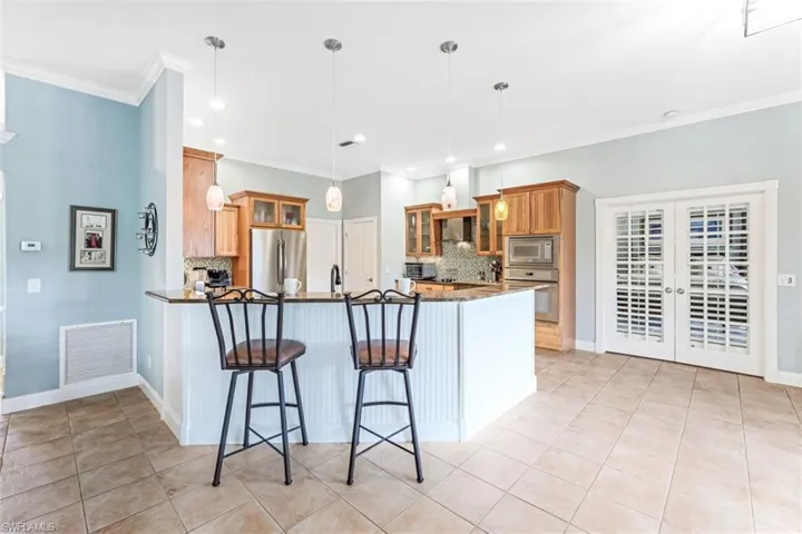 Kitchen featuring a breakfast bar, backsplash, light tile patterned floors, stainless steel appliances, and kitchen peninsula