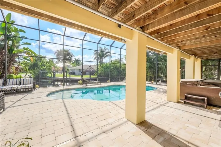View of swimming pool featuring a hot tub, glass enclosure, and a patio