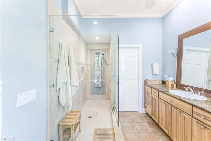 Bathroom with crown molding, vanity, walk in shower, and tile patterned floors