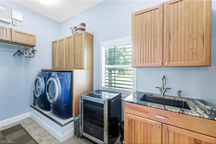 Laundry room featuring separate washer and dryer, sink, wine cooler, cabinets, and light tile patterned floors