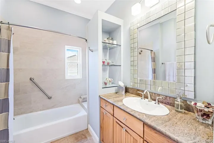 Bathroom with tile patterned floors, ornamental molding, vanity, and shower / tub combo