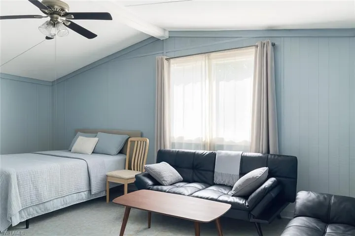 Bedroom featuring carpet flooring, ceiling fan, and wooden walls