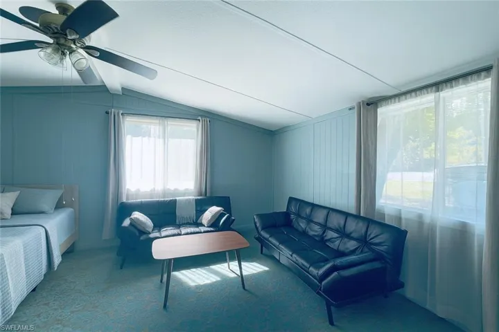 Living room featuring carpet, wood walls, and ceiling fan