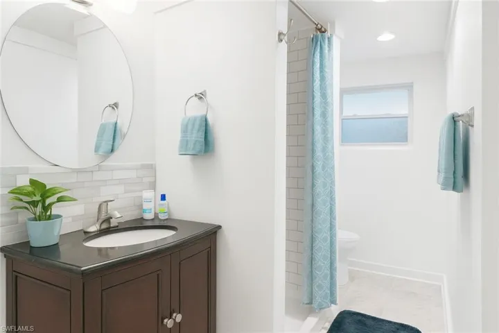 Bathroom featuring vanity, a shower stall, and tasteful backsplash