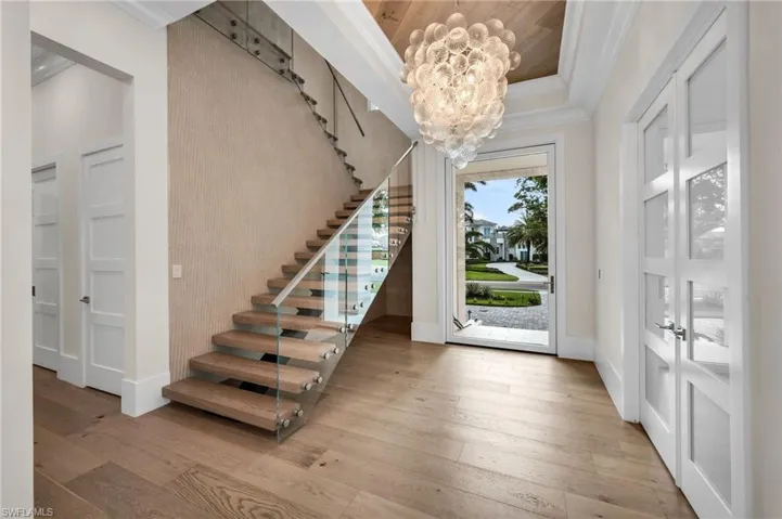 Impressive entrance with pivot style front door, glass stairway railing
