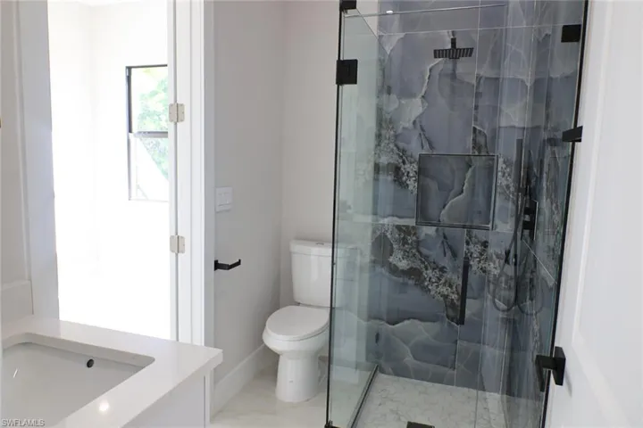Bathroom with vanity and a marble finish shower
