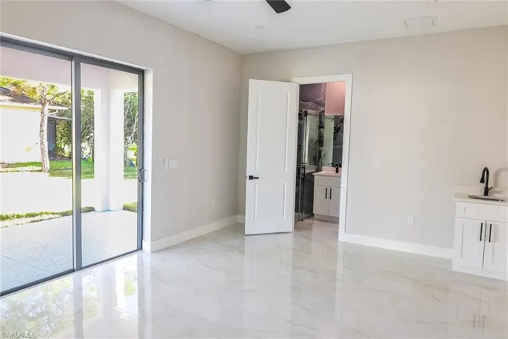 Unfurnished bedroom featuring connected bathroom, access to outside, ceiling fan, and light marble finish flooring