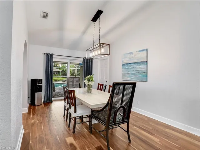 Dining space with wood finished floors, lofted ceiling, and arched walkways