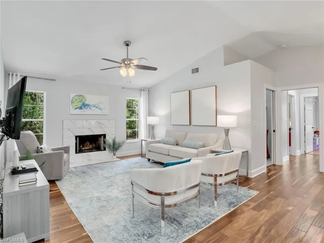 Living area with ceiling fan, vaulted ceiling, a fireplace, and Acacia wood  floors