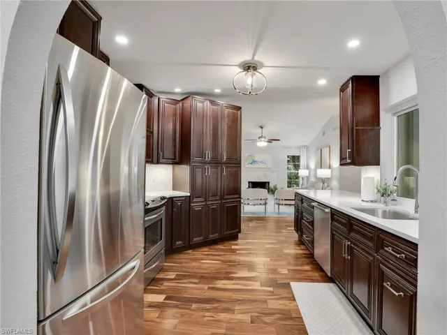 Kitchen with stainless steel appliances, light wood-style flooring, a fireplace, light countertops, and open floor plan