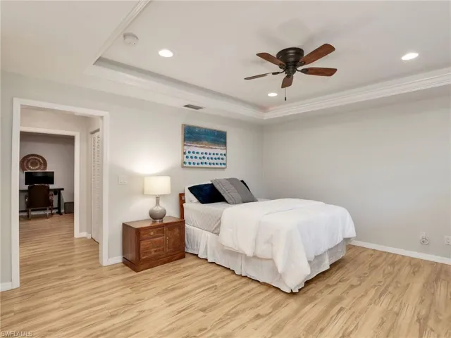 Bedroom with a tray ceiling, light wood-style floors, recessed lighting, and ceiling fan