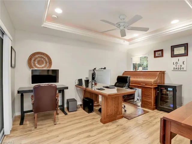 Office space with a tray ceiling, wood finished floors, crown molding, a ceiling fan, and recessed lighting
