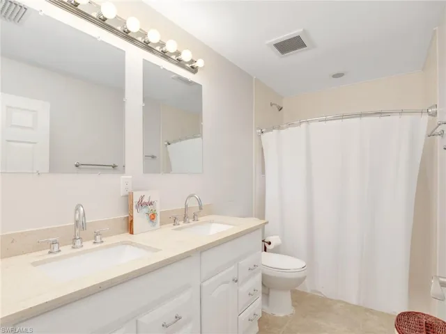 Full bath with double vanity, a shower with shower curtain, and tile patterned flooring