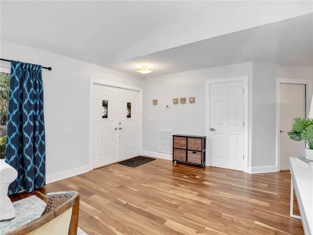 Foyer entrance featuring light wood floors and vaulted ceiling
