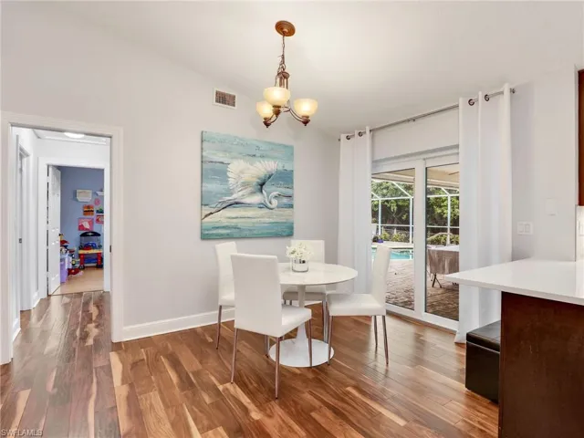 Dining space featuring a chandelier, wood finished floors, and vaulted ceiling