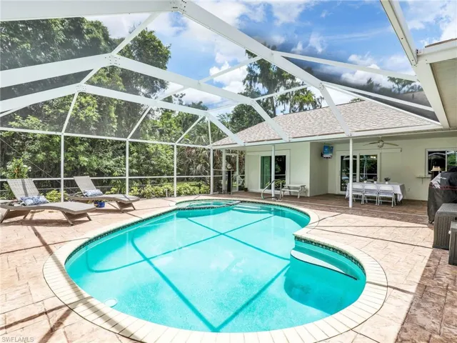 View of swimming pool featuring a patio area, ceiling fan, glass enclosure, and a pool with connected hot tub