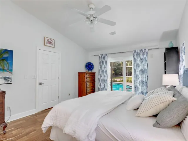 Bedroom featuring access to outside, lofted ceiling, light wood-type flooring, and a ceiling fan