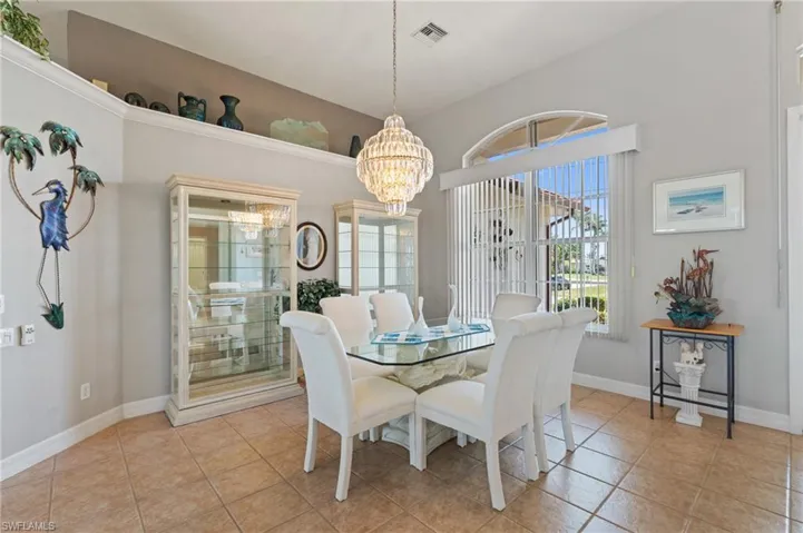 Dining space featuring visible vents, a towering ceiling, light tile patterned flooring, and an inviting chandelier