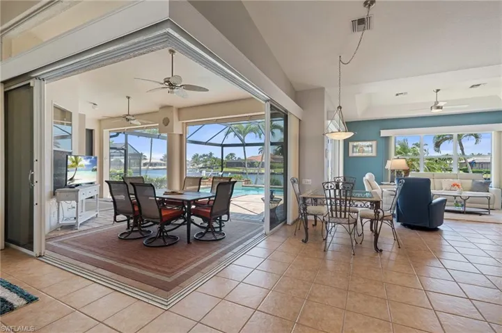 Dining space featuring ceiling fan, a raised ceiling, a sunroom, light tile patterned floors, and visible vents