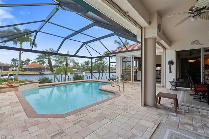 Outdoor pool featuring a water view, ceiling fan, a lanai, and a patio area