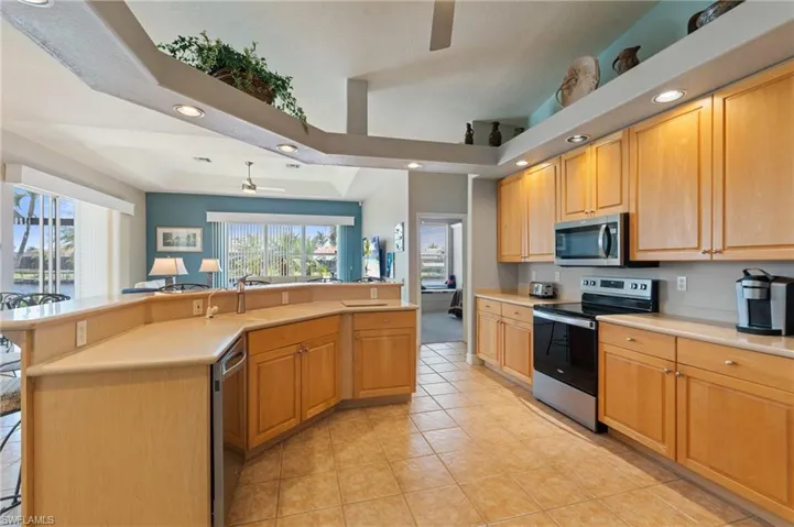 Kitchen with ceiling fan, appliances with stainless steel finishes, a sink, a tray ceiling, and recessed lighting