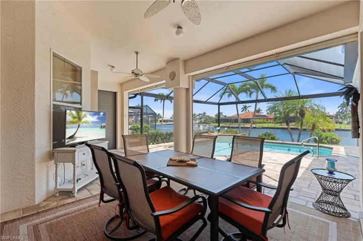 View of patio / terrace with a lanai, ceiling fan, outdoor dining space, and an outdoor pool