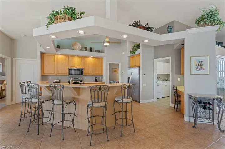 Kitchen with a high ceiling, a breakfast bar area, stainless steel appliances, and recessed lighting