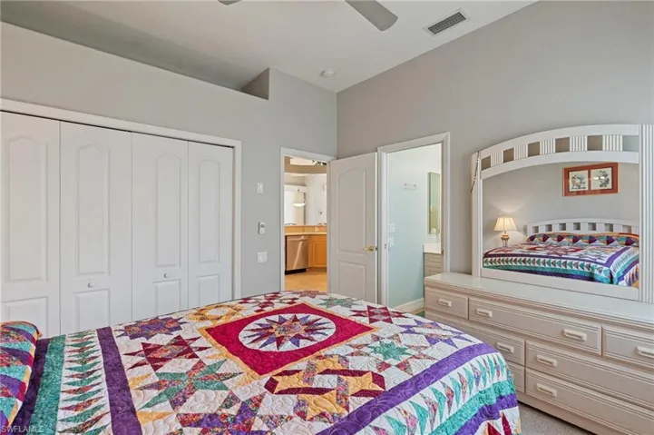 Bedroom featuring a ceiling fan, visible vents, vaulted ceiling, a closet, and ensuite bathroom