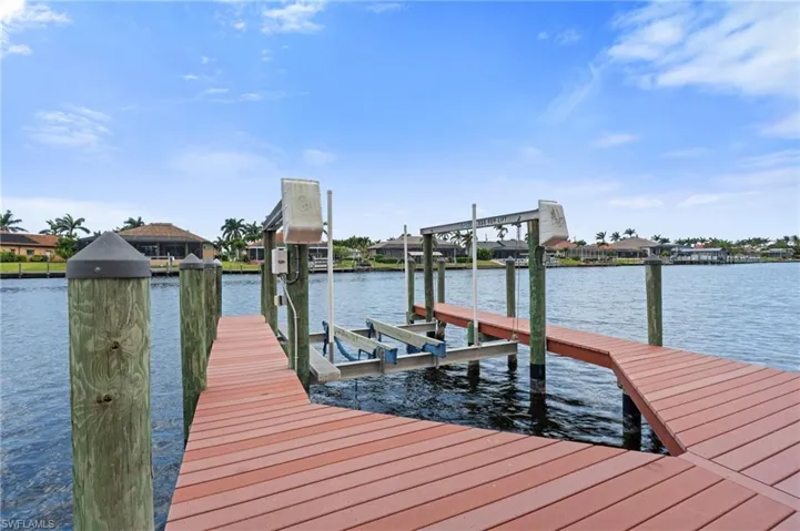 Dock area featuring a water view, boat lift, and a residential view