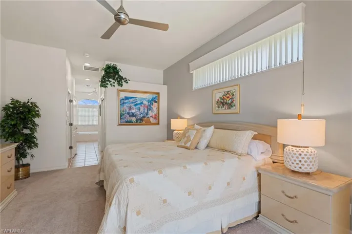 Bedroom with light colored carpet, baseboards, ensuite bathroom, and visible vents