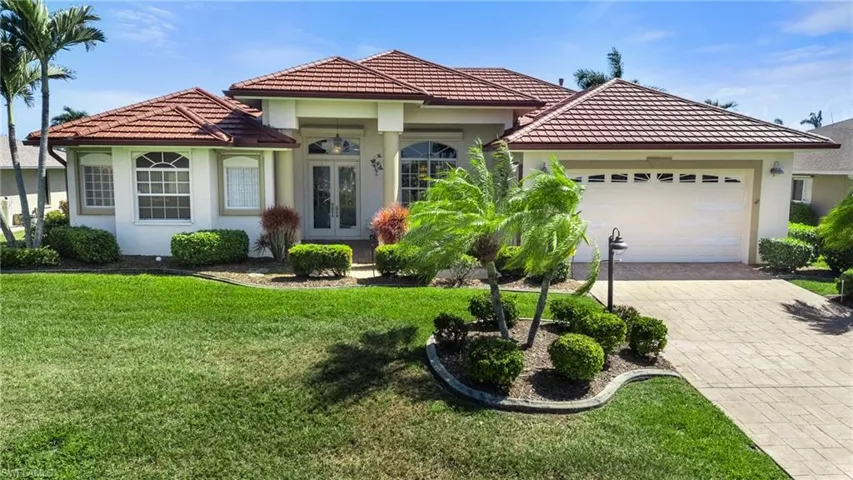 Mediterranean / spanish-style house with a garage, driveway, french doors, and a tile roof