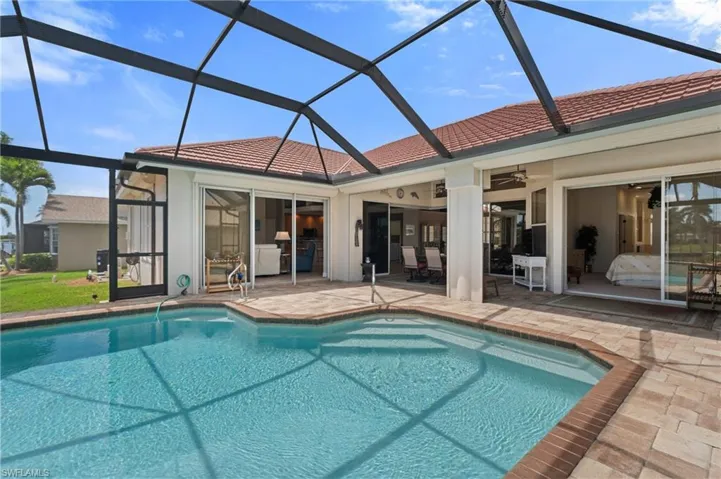 Back of property with a ceiling fan, a patio area, a tile roof, and an outdoor pool