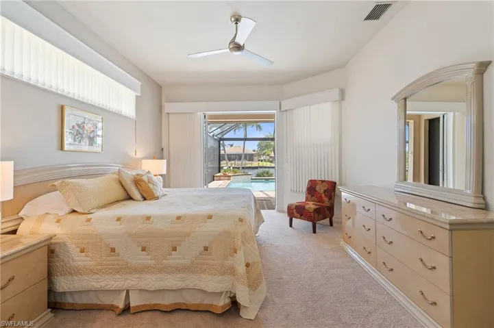 Bedroom with access to outside, light colored carpet, arched walkways, a ceiling fan, and visible vents