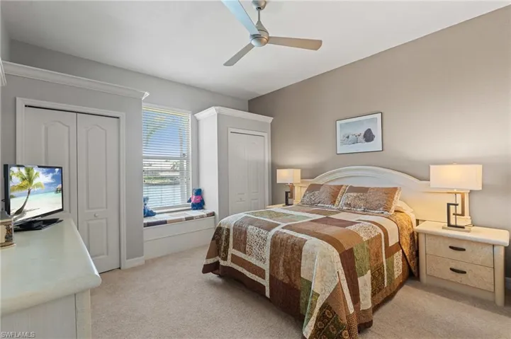 Bedroom with light colored carpet, a ceiling fan, and multiple closets