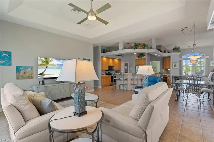 Living room featuring visible vents, a ceiling fan, a raised ceiling, and light tile patterned floors