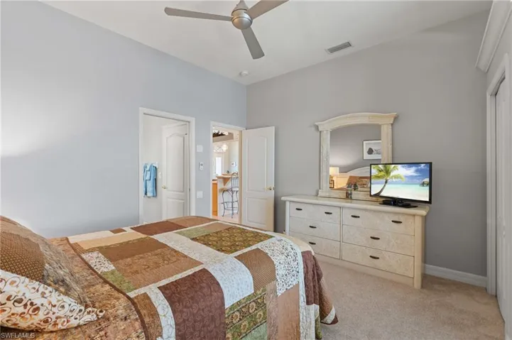 Bedroom featuring light colored carpet, ceiling fan, visible vents, and baseboards