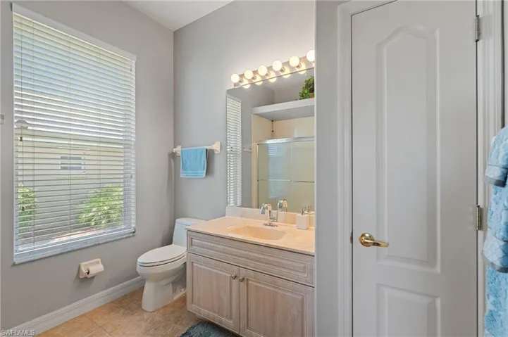 Full bathroom featuring vanity, toilet, tile patterned floors, baseboards, and a shower stall