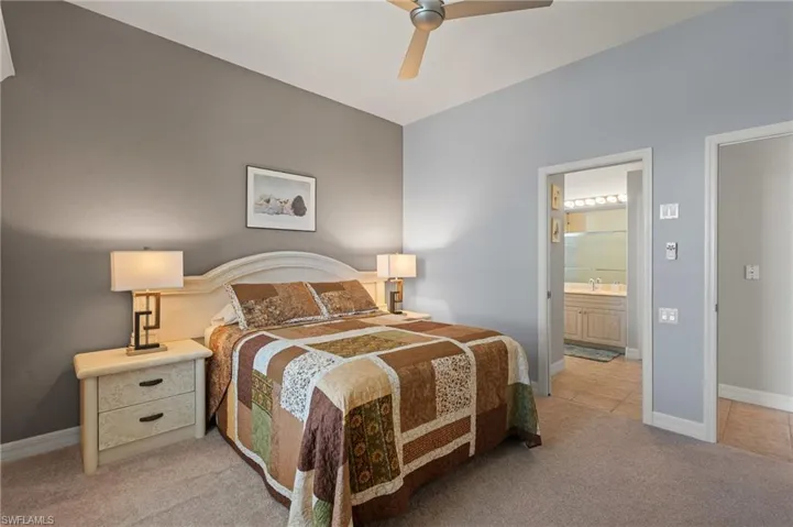 Bedroom featuring connected bathroom, light carpet, a sink, a ceiling fan, and baseboards
