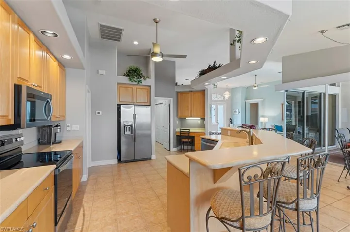 Kitchen with a breakfast bar area, a ceiling fan, appliances with stainless steel finishes, a sink, and recessed lighting