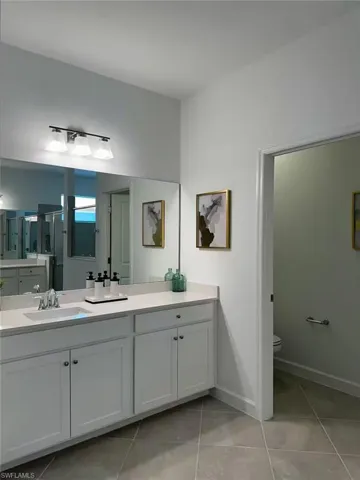 Full bath with vanity, light tile patterned flooring, and an enclosed shower