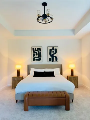 Bedroom with light carpet and a tray ceiling