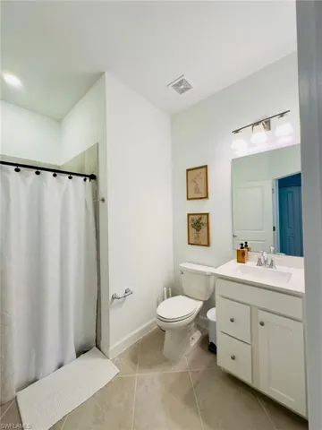 Full bath featuring a stall shower, vanity, and light tile patterned floors