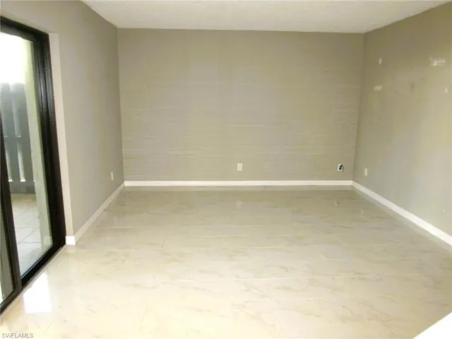 Unfurnished room featuring baseboards and light marble finish floors