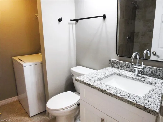 Bathroom featuring vanity, washer / clothes dryer, light tile patterned flooring, and a shower